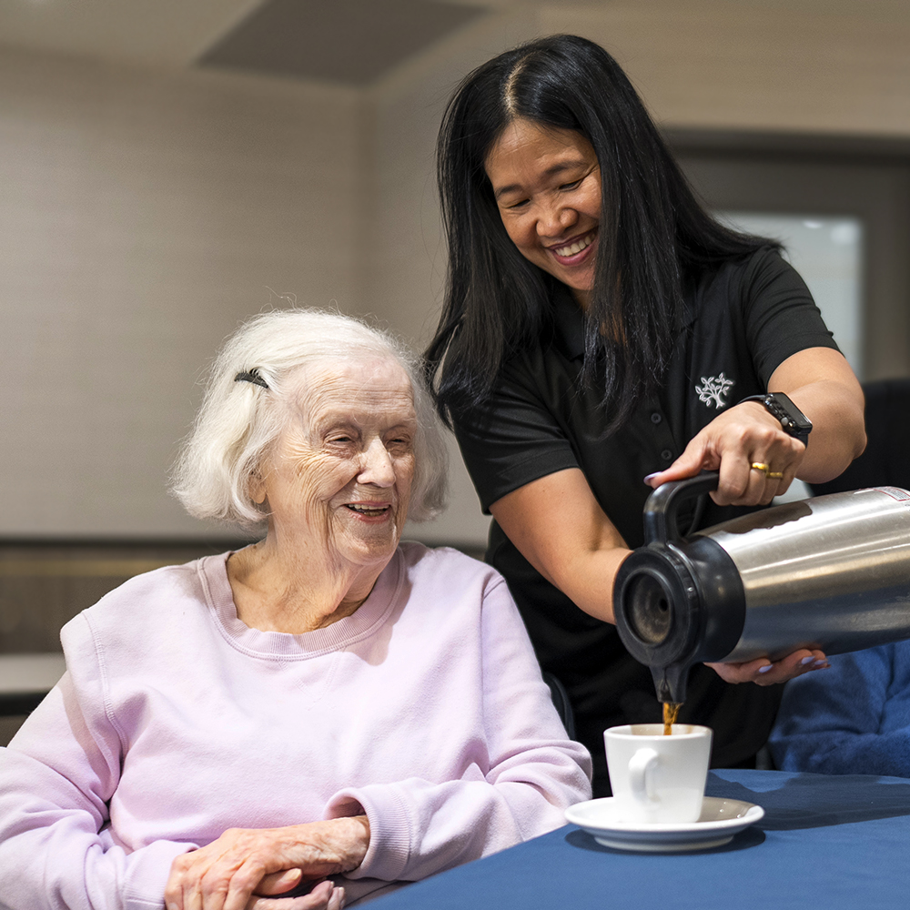 Team member pouring coffee and sharing a warm moment with a resident during a short stay at Atrium Retirement Residence in Orillia